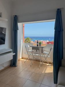 un soggiorno con tavolo e sedie e una grande finestra di Apartamento Horizonte El Puertito de Güímar a Puertito de Güímar