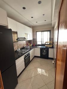 a kitchen with white cabinets and a black appliance at Résidence oasis beach mansouriah in Mohammedia
