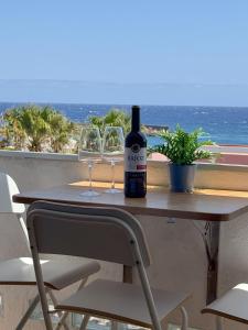 una bottiglia di vino seduta su un tavolo con due bicchieri di Apartamento Horizonte El Puertito de Güímar a Puertito de Güímar
