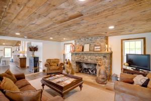a living room with a stone fireplace and a tv at Fire Pit and Views Crooked Lake Group Getaway! in Averill Park
