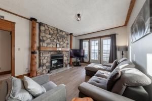 a living room with couches and a stone fireplace at Ski in - Ski out Condo, Hot Tub, Fireplace, Parking, Lake View in Mont-Tremblant
