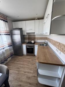 a kitchen with white cabinets and a wooden counter top at Gerasima Kondratyeva 152 in Sumy