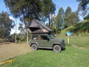 a green jeep with a tent on top of it at Zona de Camping Hostal Las Hamacas in Villamaría