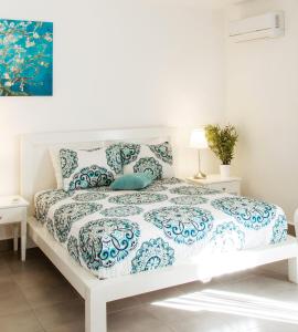 a white bed with a blue and white comforter at SOL CARIBE VILLAGE - STUDIOS DELUXE - playa LOS CORALES in Punta Cana