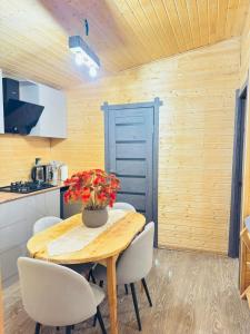 eine Küche mit einem Holztisch mit weißen Stühlen und einer Holzdecke in der Unterkunft ToonToonik in Hors