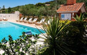 a swimming pool with lounge chairs next to a house at Apartments Spomenka in Mundanije