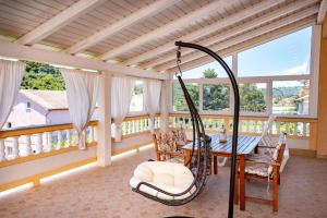 a porch with a swing and a table at Apartments Spomenka in Mundanije
