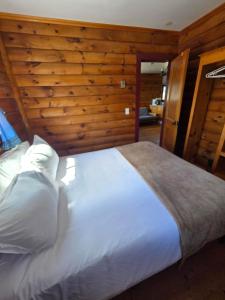 a large white bed in a room with wooden walls at Hunts Point 2-BR Coastal Retreat - Cottage # 1 in Summerville Centre