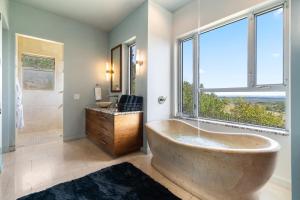 a bathroom with a large tub and a window at Luxury 7BR Hill Country Gem Hot Tub & Barndominium in Dripping Springs