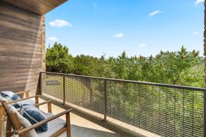 a balcony with a chair and a view of trees at Luxury 7BR Hill Country Gem Hot Tub & Barndominium in Dripping Springs