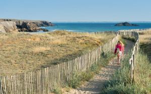 a woman walking along a fence at the beach at Maison 3 chambres 250 m de la mer in La Trinité-sur-Mer