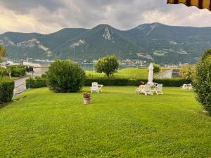 a green yard with chairs and an umbrella and mountains at BADIA del LAGO CLUSANE in Clusane sul Lago