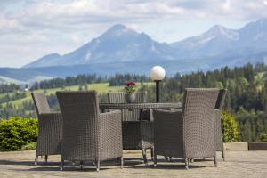 a table and chairs with mountains in the background at Hotel REDYK Ski&Relax in Ząb