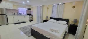 a white bedroom with a bed and a kitchen at Oceanview Suites in Saint Georgeʼs