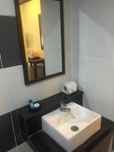 uma casa de banho com um lavatório branco e um espelho. em Sayy Haa Inn em Pantai Cenang