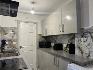 une cuisine avec des armoires blanches et un évier dans l'établissement Modern Apartment near Etihad Stadium & C o-op Live, à Manchester 5 autres photos