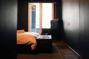 Un dormitorio con una cama, una silla y una ventana en Gold Crest Mall Luxury Apartments with Balcony by NestNow in DHA Phase 4 Lahore, en Lahore