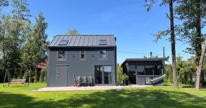 a small gray house with two chairs in a yard at Mazurski Chill House in Małkinie