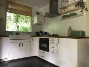 a kitchen with white cabinets and a window at Het Boshuisje in Nunspeet