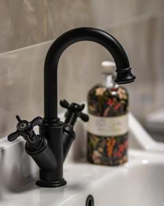 ein Waschbecken mit einem schwarzen Wasserhahn und einer Flasche Seife in der Unterkunft Old Castle Cottage Retreat in Oxford + 27 Fotos