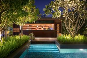 a pool in the middle of a garden with a bar at JEN Singapore Orchardgateway by Shangri-La in Singapore