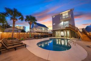 a swimming pool in front of a house with palm trees at Seaside Bliss at Treasure Circle in Panama City Beach