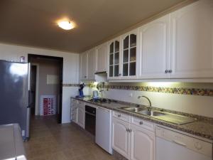 a kitchen with white cabinets and a sink and a refrigerator at Apartment Valeriana in Lagos