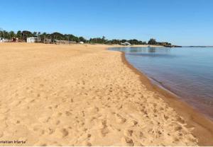 a beach with footprints in the sand and water at La LELITA in Paso de la Patria