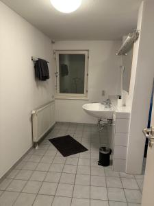 a white bathroom with a sink and a mirror at Voll ausgestattetes Apartment direkt in der City in Herrenberg +4 photos