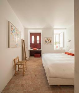 a bedroom with a large white bed and a chair at Danna Portuguese Design House Porta 11 in Tavira