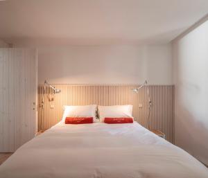 a bedroom with a large white bed with two red pillows at Danna Portuguese Design House Porta 11 in Tavira