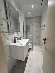 a white bathroom with a sink and a shower at Serenita Hotel in Vlorë +65 photos