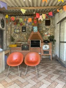 two orange chairs sitting in front of a brick oven at Chácara do vovô kiko in Santana de Parnaíba