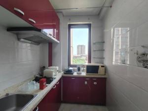 d'une cuisine avec des placards rouges, un évier et une fenêtre. dans l'établissement Central Street Apartment 1, à Harbin