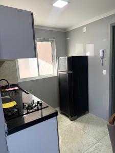 een keuken met een zwarte koelkast en een raam bij Confort Flat Campina Grande in Campina Grande