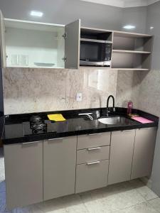 een keuken met een spoelbak en een magnetron bij Confort Flat Campina Grande in Campina Grande