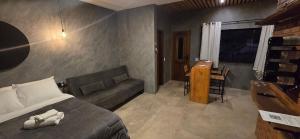 une chambre avec un lit, un canapé et une table dans l'établissement Villa da Serra Studio com ar condicionado Quente/frio, à Conceição da Ibitipoca