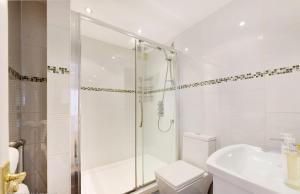 a bathroom with a shower and a toilet and a sink at Estatesmen Harrods Knightsbridge Apartment in London