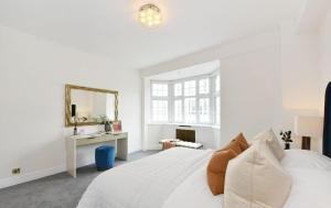a white bedroom with a white bed and a mirror at Estatesmen Harrods Knightsbridge Apartment in London