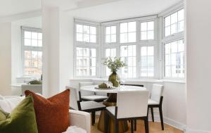 a white dining room with a table and chairs at Estatesmen Harrods Knightsbridge Apartment in London +12 photos
