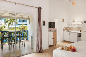 a bedroom with a bed and a kitchen with a table at Island Bliss Condo in Koolbaai