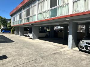 a building with cars parked in a parking lot at Airway Motel in Brisbane