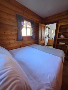 a bedroom with a white bed in a wooden room at Hunts Point 1-BR Coastal Retreat - Cottage # 6 in Summerville Centre +10 photos