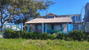 ein Haus mit einer Hängematte vor einem Gebäude in der Unterkunft Casa beiramar, vista mar e pinheiros, pé na areia in Xangri-lá