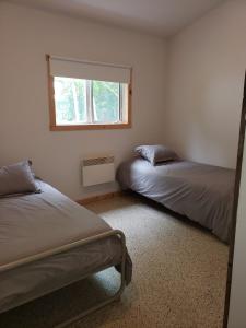 une chambre avec deux lits et une fenêtre dans l'établissement Chalet au lac Saint-Jean, à Dolbeau-Mistassini