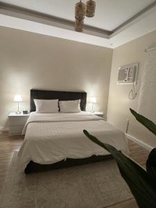 a white bedroom with a large bed with two lamps at شقق فندقية هادئة بحي السلامة in Jeddah