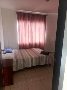 a small bedroom with a bed and a pink window at Urbanización Ceibo Real in Manta