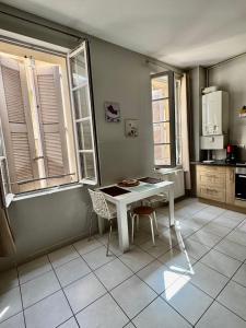 a kitchen with a white table and two windows at La Parenthèse Enchantée Avignon in Avignon