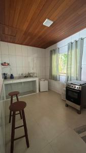 a kitchen with a stove and a stool in it at Carneiro's House in Praia de Araçatiba