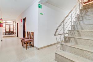 a hallway with two chairs and stairs in a house at Hotel O Hari Singh High Street Formerly City Star in Jawāharnagar